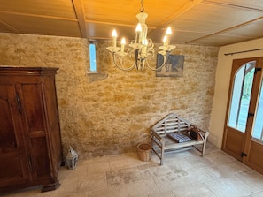 A rustic room with a wooden bench, a chandelier, and a stone wall. - Basel Landskron Haus (LEYMEN)