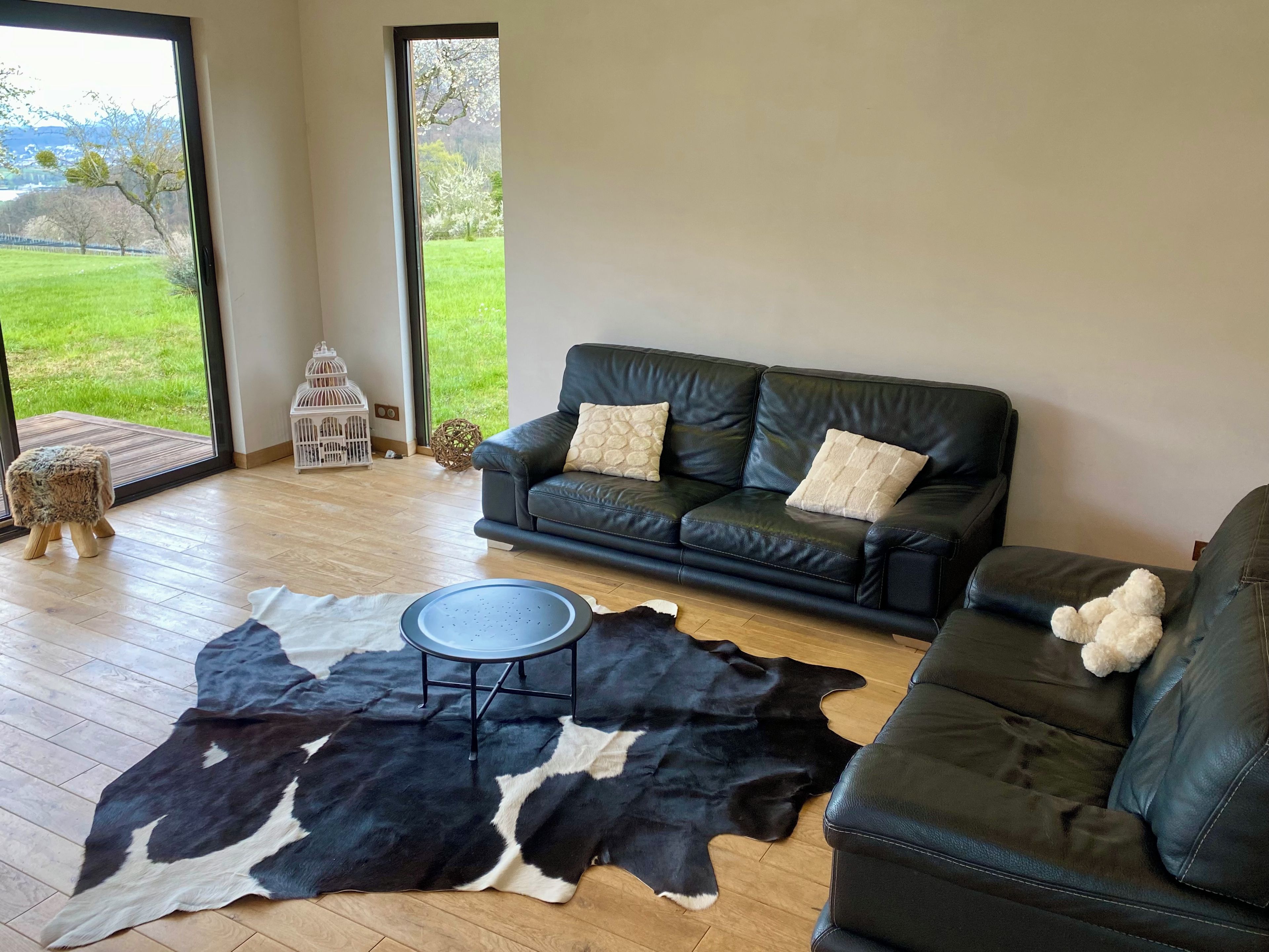 A living room with a leather sofa, a round coffee table, and a black and white cowhide rug.