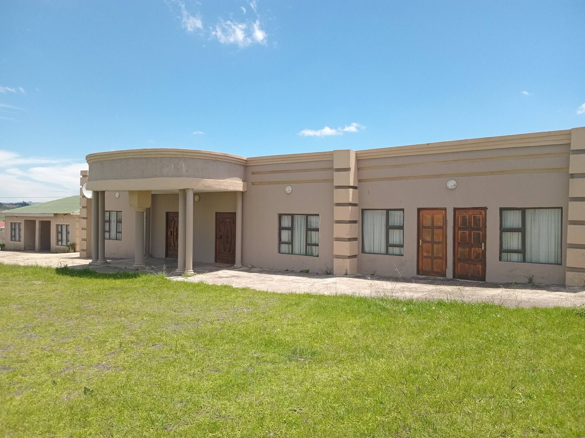Un edificio de dos pisos con techo plano, varias ventanas y un acceso cubierto.