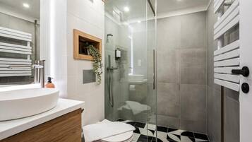 A modern bathroom with a glass-enclosed shower, a white sink, and a black-and-white patterned floor.