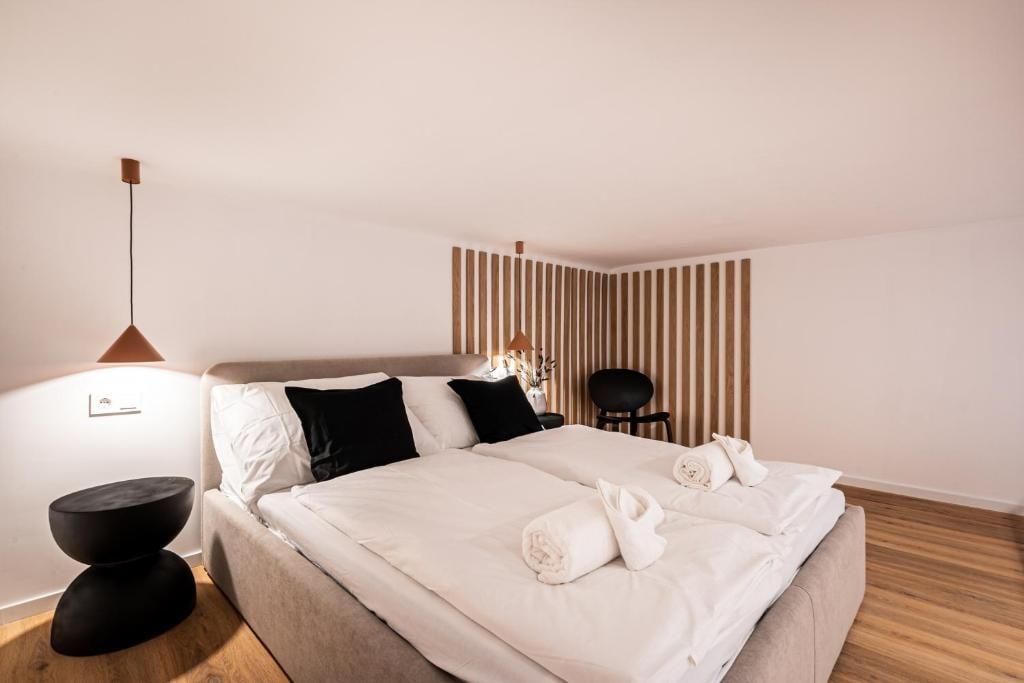 Una habitación de hotel con una cama, mesitas de noche, una silla y una pared con líneas verticales.