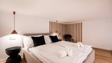 Una habitación de hotel con una cama, mesitas de noche, una silla y una pared con líneas verticales.
