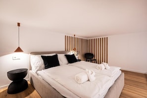 Ein Hotelzimmer mit einem Bett, Nachttischen, einem Sessel und einer Wand mit vertikalen Linien.