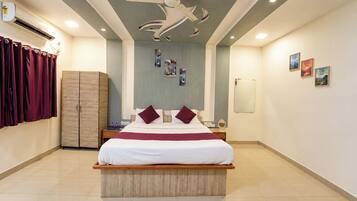 A hotel room with a bed, a wardrobe, a ceiling fan, and artwork on the walls.