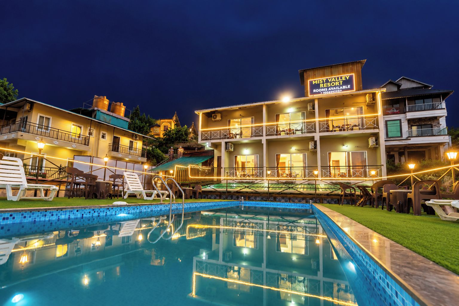 A hotel with a swimming pool, multiple balconies, and outdoor seating areas.