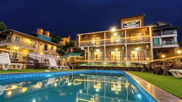 A hotel with a swimming pool, multiple balconies, and outdoor seating areas.