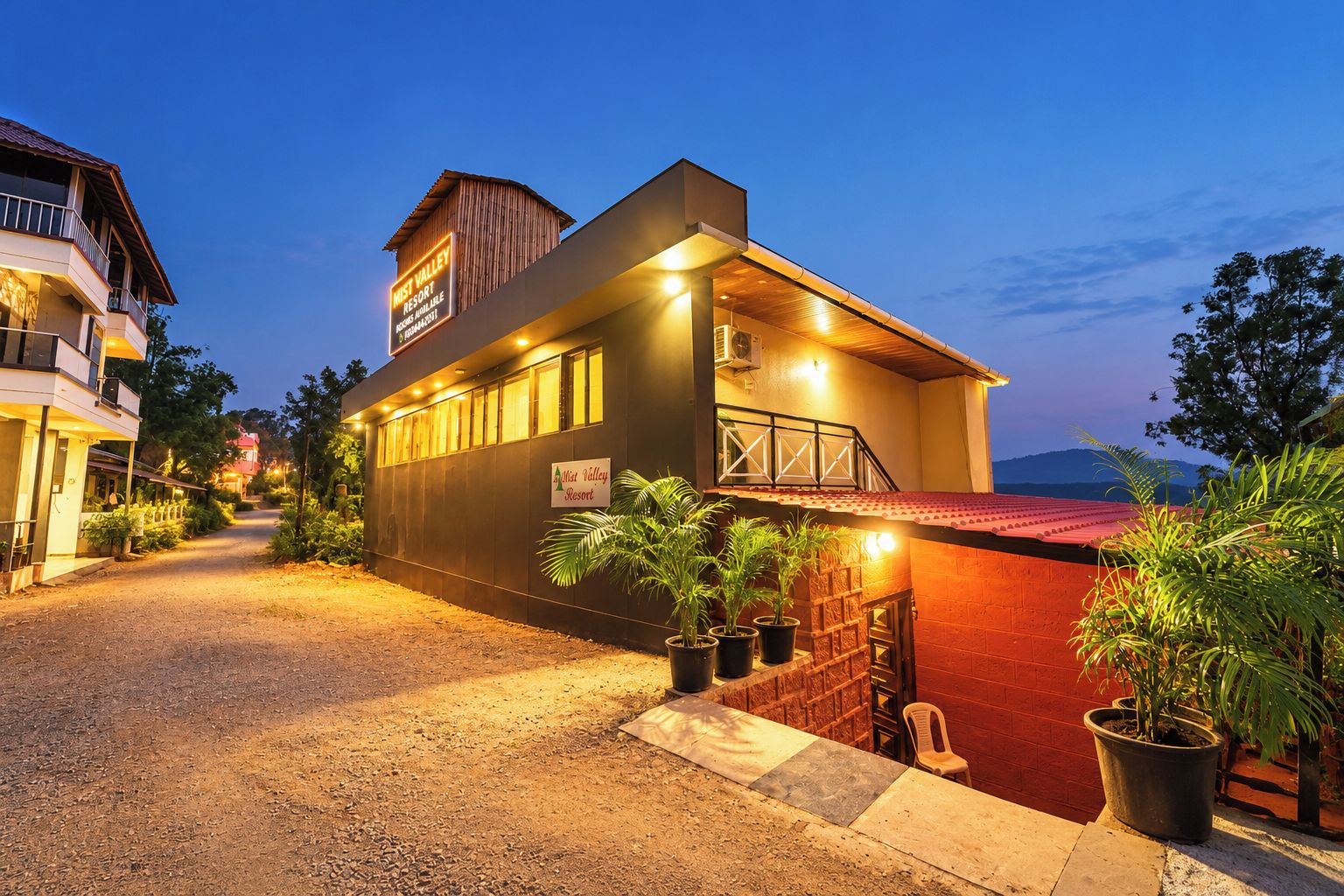 A two-story building with a sign indicating it's a resort. There are potted plants and a red brick wall in front.