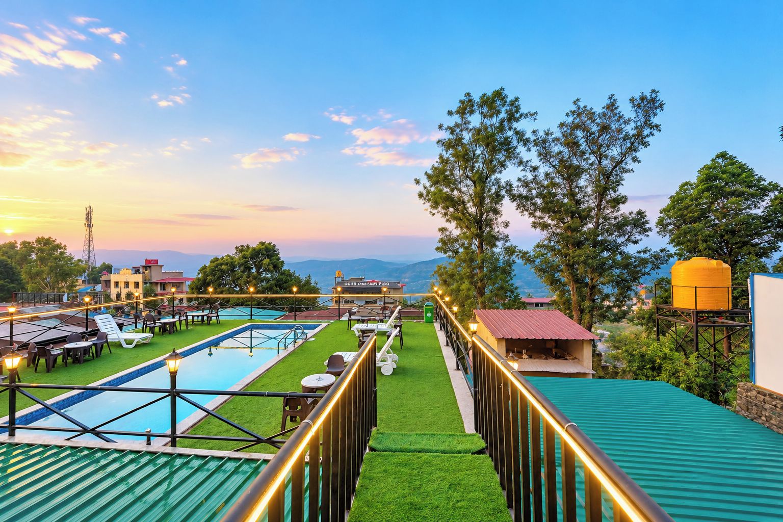 A rooftop pool area with a view of the mountains, a restaurant, and a water tank.