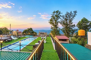 A rooftop pool area with a view of the mountains, a restaurant, and a water tank. - Mist Valley Resort (Mahabaleshwar)