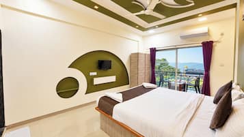 A hotel room with a bed, a TV, a balcony with a view, and a ceiling fan.