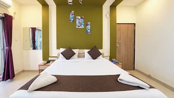Quarto de hotel com uma cama grande, mesa de cabeceira, espelho, porta e obras de arte na parede.