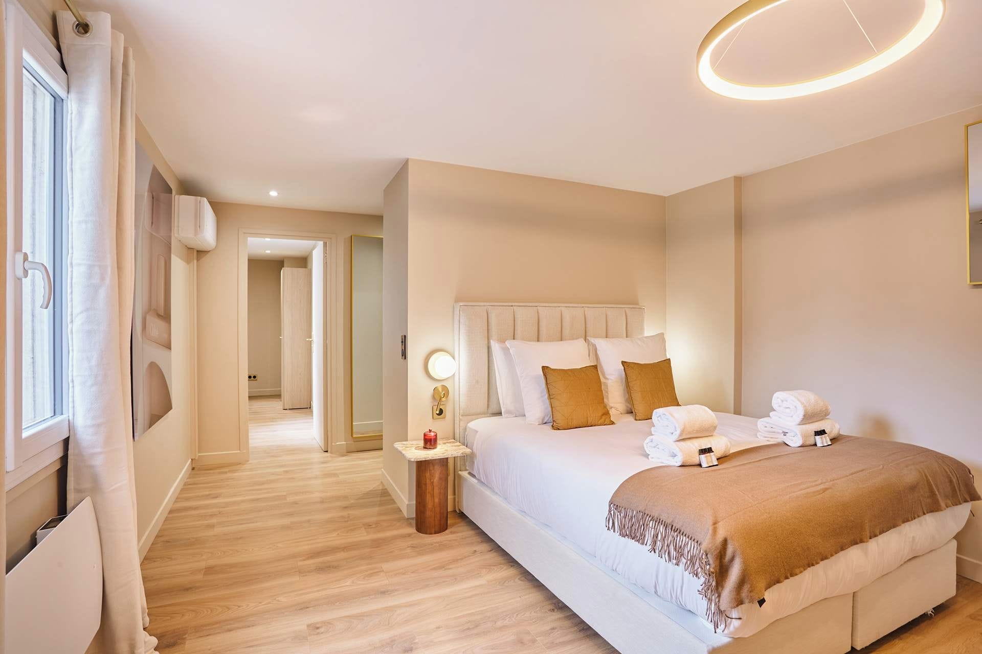 A hotel room with a large bed, bedside table, and a mirror.