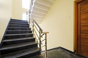 Una escalera con escalones de mármol negro y barandilla metálica que conduce a una plataforma.