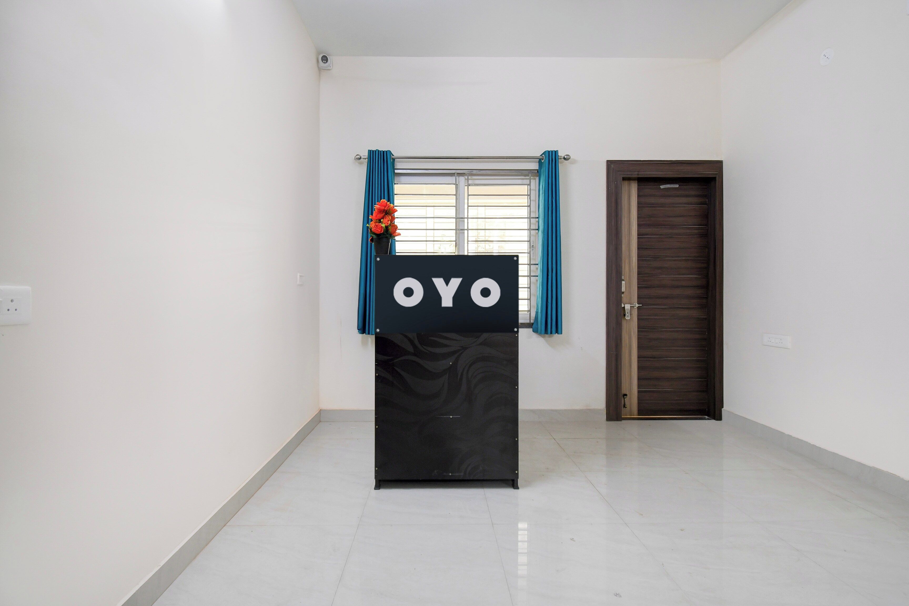 A room with a black podium, a window with blue curtains, and a closed door.
