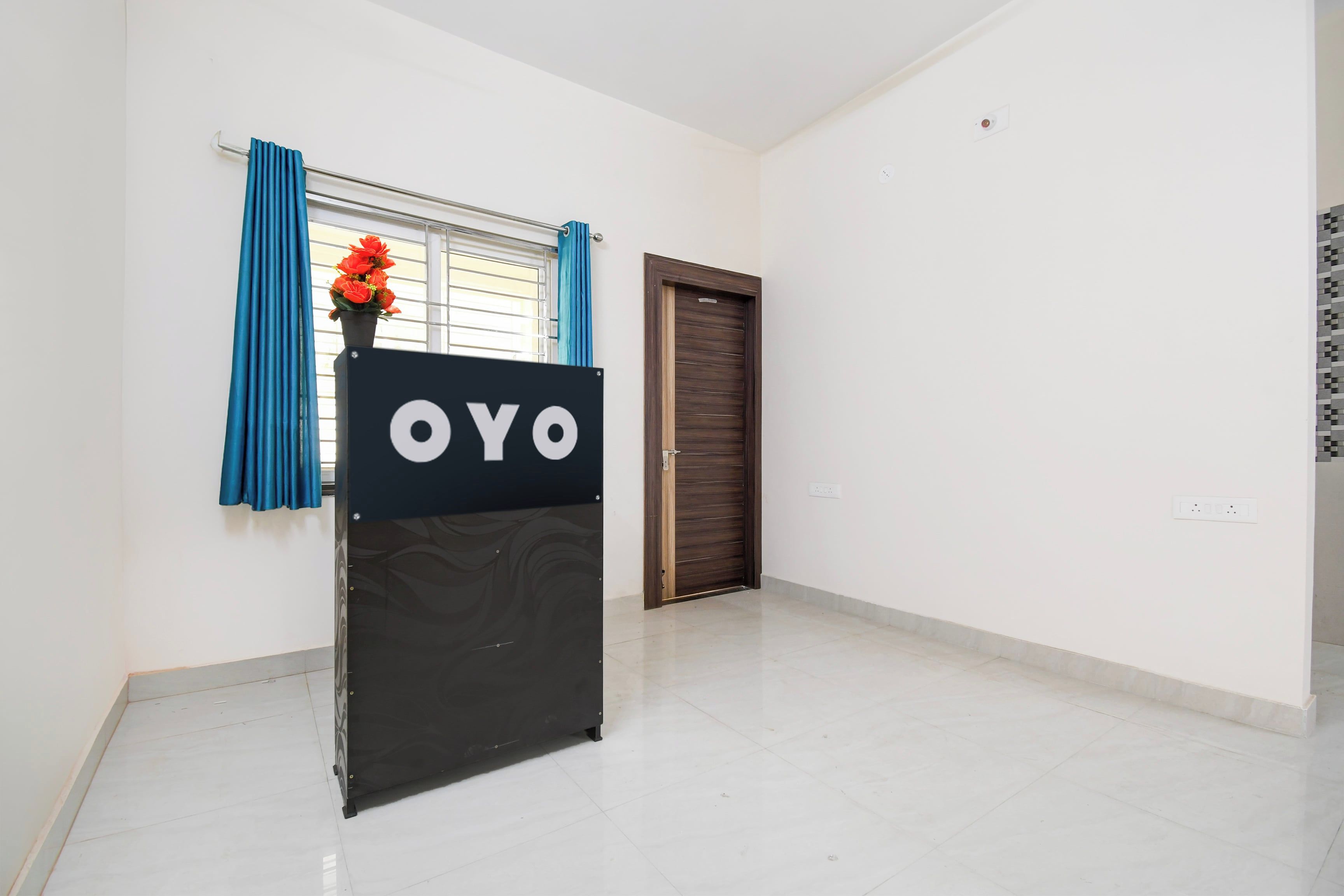A room with a black sign reading 'OYO' on a stand, a window with blue curtains, a door, and a tiled floor.