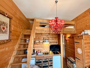 A wooden interior with a kitchen area, a staircase, and a chandelier. - Apartment Near Mont-dore Centre (Mont-Dore)