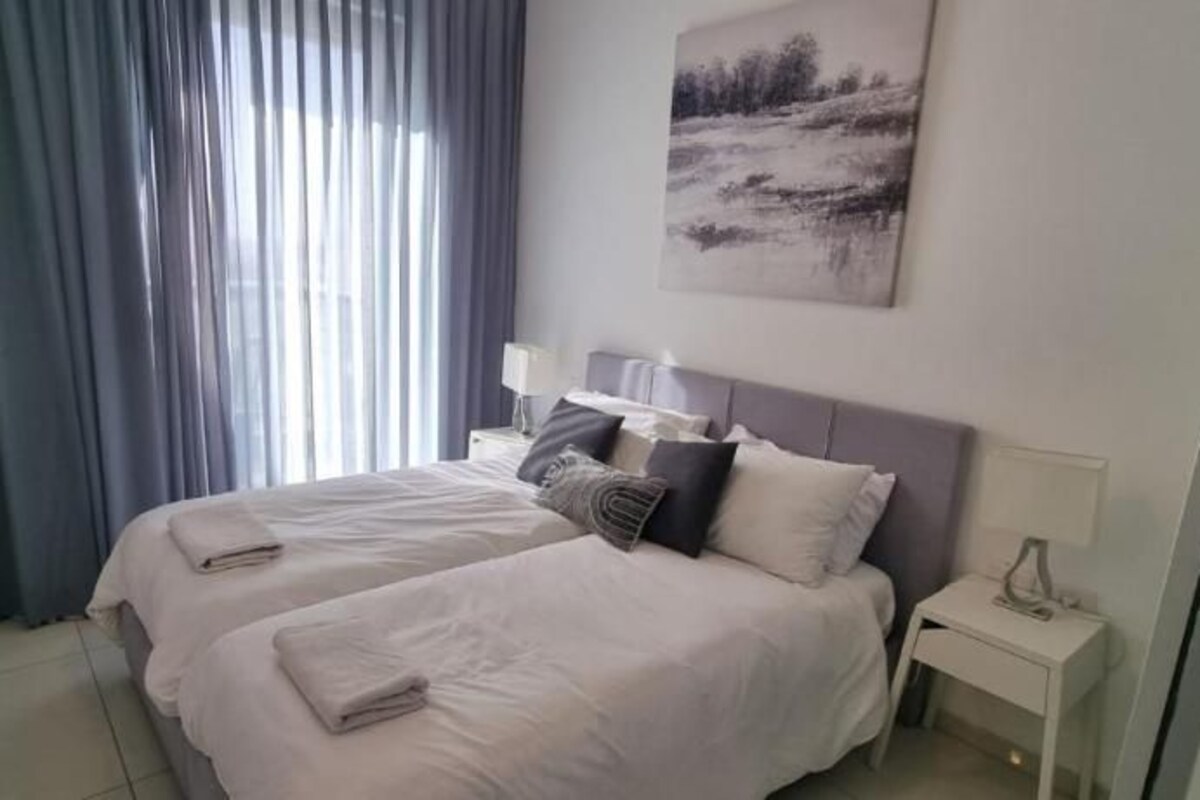 A hotel room with a bed, a bedside table, a lamp, and a painting on the wall.