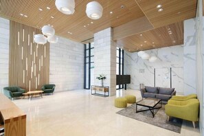 A spacious lobby with a high ceiling, modern furniture, and a marble wall. - Jtowers G Royal Suites (Jerusalem)