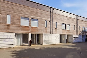 Un edificio moderno con techo plano, amplios ventanales y una zona de acceso cubierta.