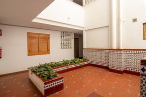 A spacious courtyard with terracotta tiled flooring, a wooden door, a white wall with decorative tiles, and a window with wooden shutters. - Casa del Sol Playa del los Locos Torrevieja (Torrevieja)
