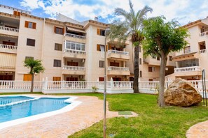 A multi-story hotel with balconies, a swimming pool, and a well-maintained lawn. - Casa del Sol Playa del los Locos Torrevieja (Torrevieja)