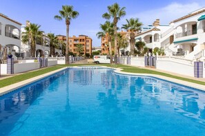 A swimming pool surrounded by buildings with balconies and palm trees. - The Couthy Casa VillaMartin (Alicante)