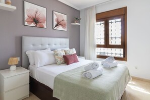 A neatly arranged bedroom with a bed, pillows, a nightstand, a lamp, and a window with curtains. - The Couthy Casa VillaMartin (Alicante)
