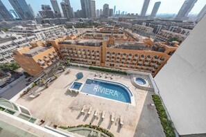Ein Hotel mit Dachpool namens 'RIVIERA', umgeben von einem Innenhof mit Liegestühlen und einem Schwimmbecken.