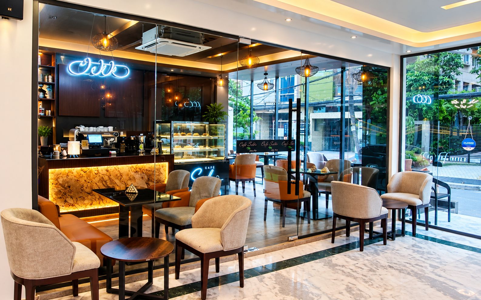 A cafe with a marble floor, seating area with chairs and tables, a coffee bar, and a neon sign.
