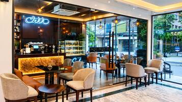 A cafe with a marble floor, seating area with chairs and tables, a coffee bar, and a neon sign.