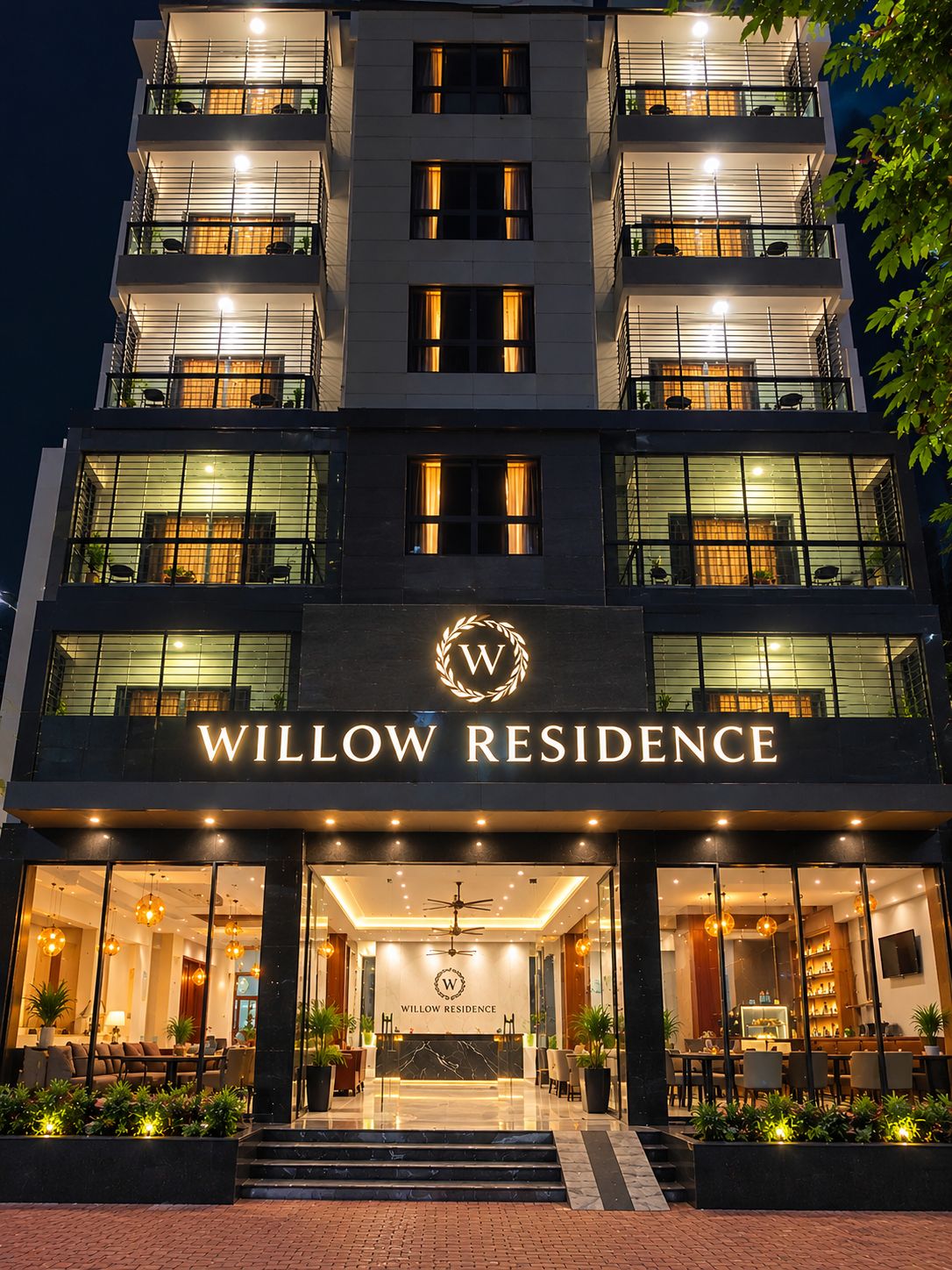 A multi-story hotel with a prominent 'WILLOW RESIDENCE' sign, large windows, and a well-lit entrance.