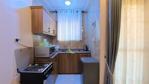 Eine kompakte Küche mit Gasherd, Mikrowelle, Spüle und Holzschränken.