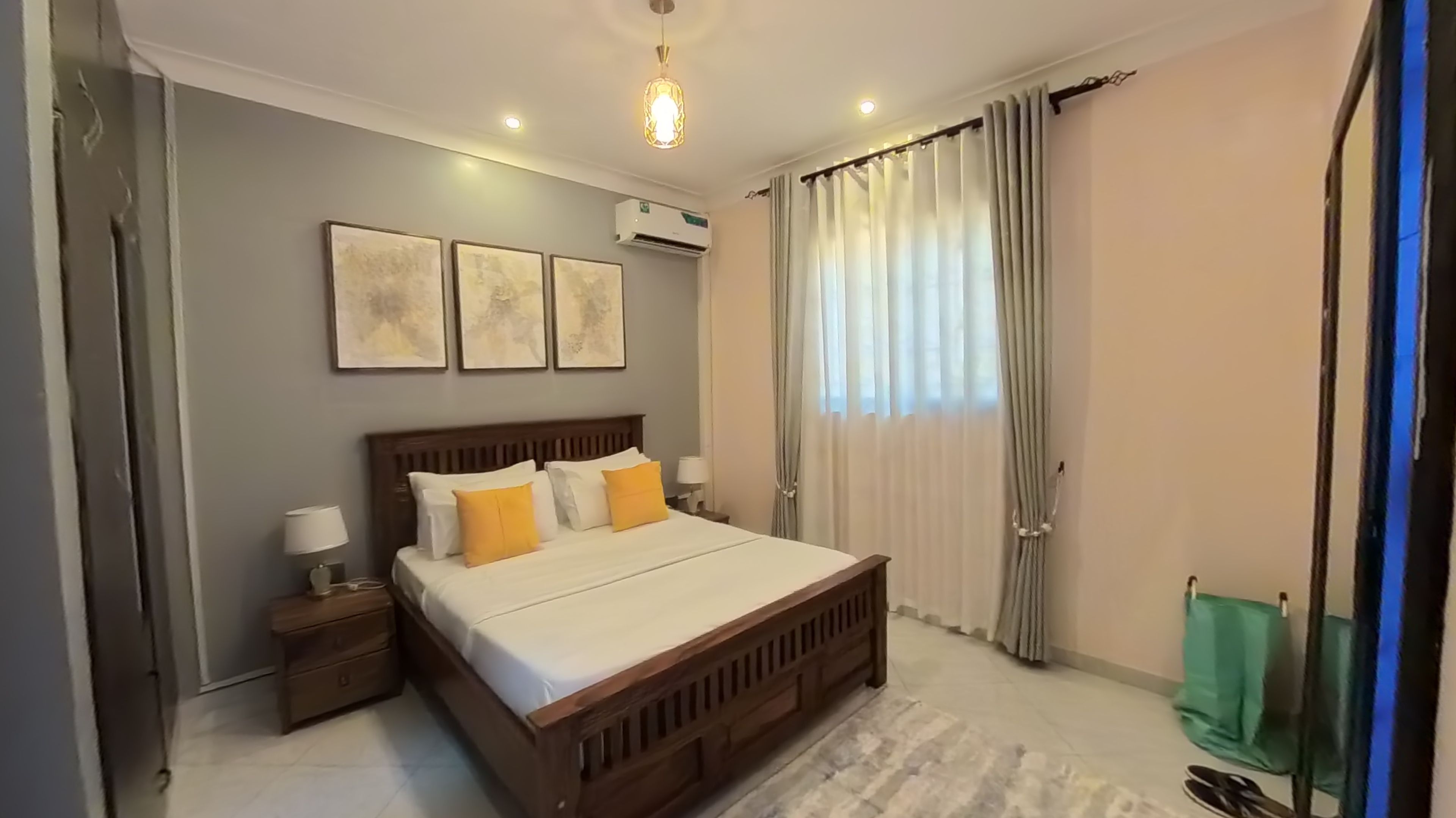 A bedroom with a wooden bed, a nightstand, a wall-mounted air conditioner, and a window with curtains.