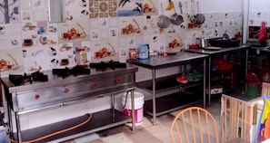 A kitchen with stainless steel appliances, a tiled backsplash, and various kitchen utensils. - My Garden house (Kathmandu)