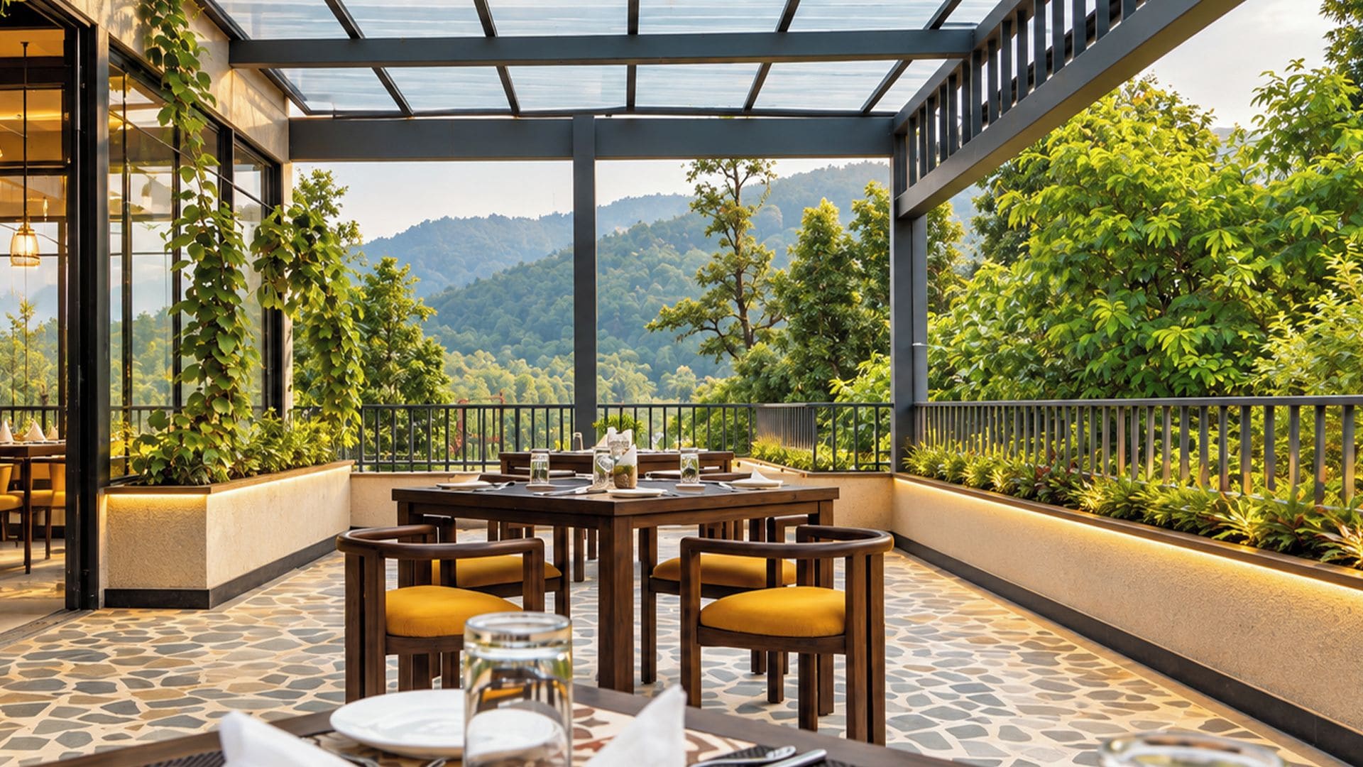 An outdoor dining area with a table set for four, surrounded by chairs with yellow cushions, overlooking a mountainous landscape.