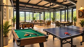 A recreational area with pool tables, a foosball table, and a ping pong table.