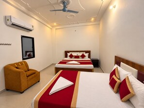 A hotel room with a bed, a sofa, a ceiling fan, an air conditioner, and a mirror. - Shree Hanumant Palace (Ayodhya)