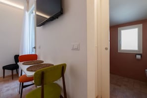 A room with a dining table, chairs, a television, and a window. - A cozy 25-square-meter studio apartment, ideal for two people, located on the fourth floor of a building (no elevator) in the central Rione Monti district, just steps away from the Imperial Forums. The apartment enjoys a prime location, very close to the (Rome)
