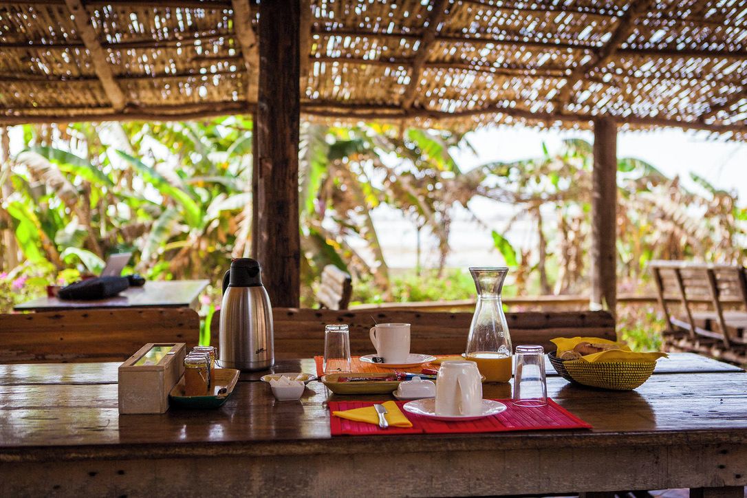A wooden table set for breakfast with various food items and a thermos.