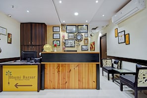 A reception desk with a wooden finish, a clock, and framed pictures on the wall.