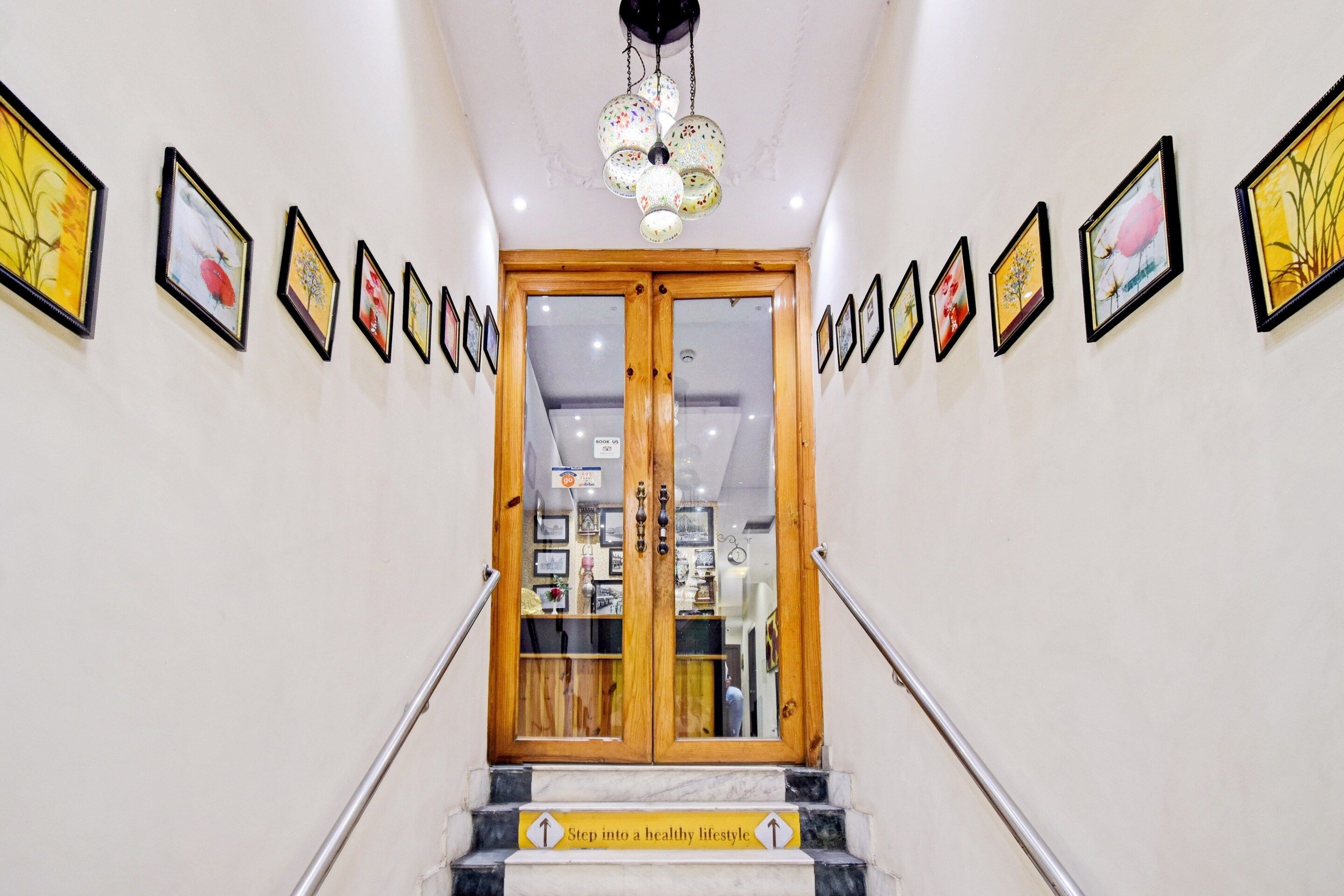 Una escalera conduce a una habitación con una puerta de madera, decorada con cuadros en las paredes.
