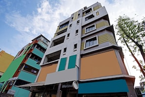 A multi-story building with a mix of commercial and residential spaces, featuring a variety of storefronts and balconies.
