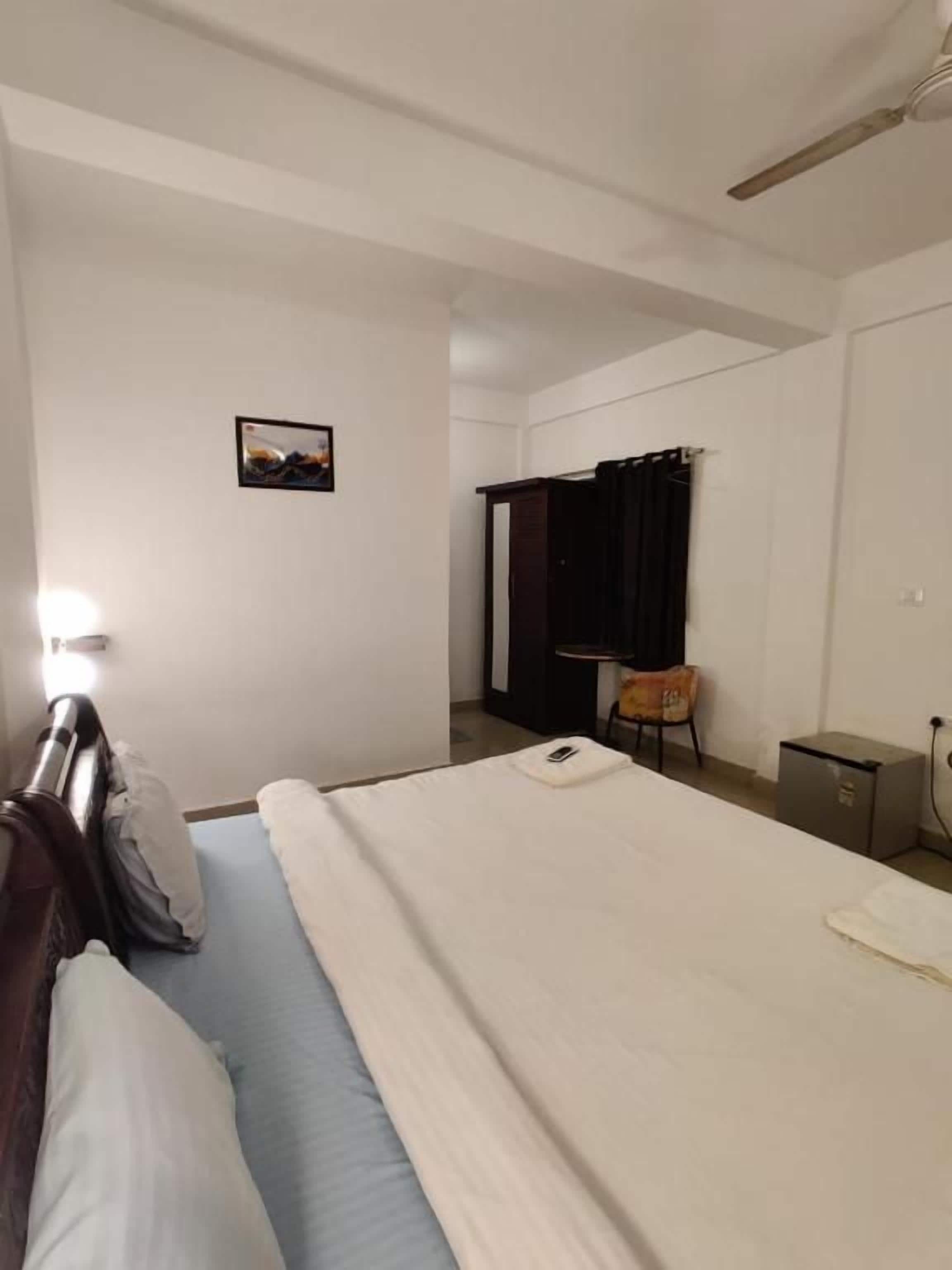 A hotel room with a bed, a chair, a desk, and a small cabinet.