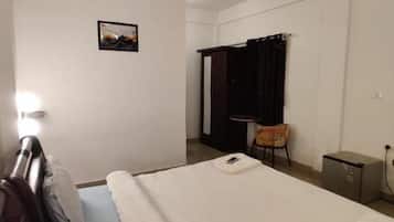 A hotel room with a bed, a chair, a desk, and a small cabinet.