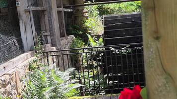A rustic wooden structure with a metal gate, surrounded by lush greenery and a wooden deck.
