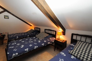 A bedroom with two beds, each with a headboard and a bedside table with a lamp.