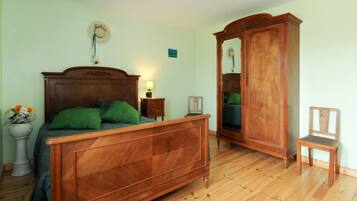 Ein Schlafzimmer mit einem hölzernen Bett, einem Nachttisch, einem Spiegel und einem Sessel.