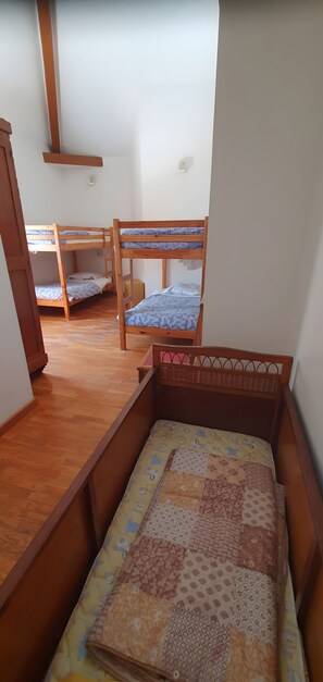 Ein Zimmer mit zwei Etagenbetten, Holzboden und einem kleinen Fenster.