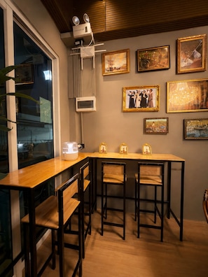 A dining area with a wooden table and chairs, a window with blinds, and artwork on the wall. - Siam Old Town BKK (Phra nakhon)