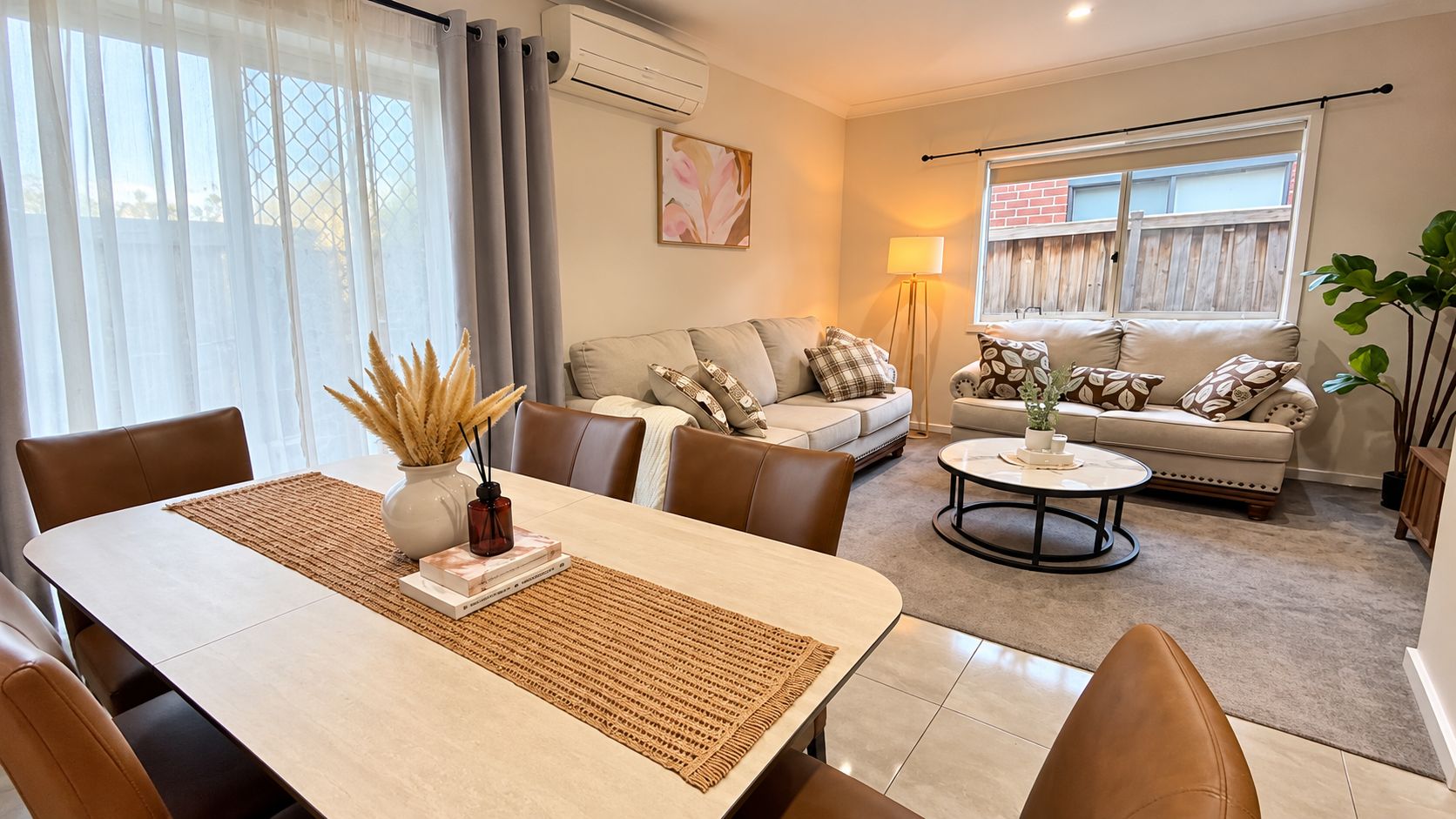 A modern living room with a dining area, featuring a sofa set, a coffee table, and a dining table with placemats.